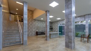 A spacious lobby with a staircase, stone walls, and a modern design. - Mansion in Greater São Paulo Area - Condominium (Caconde)