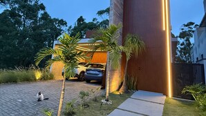 A modern house with a large wooden wall and a car parked in the driveway. - Mansion in Greater São Paulo Area - Condominium (Caconde)