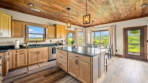 A spacious kitchen with wooden cabinets, a large island, and a view of the outdoors. - New 2025–5 Mi Dollywood–Mtn Views–1-Step–Pets (Sevierville)