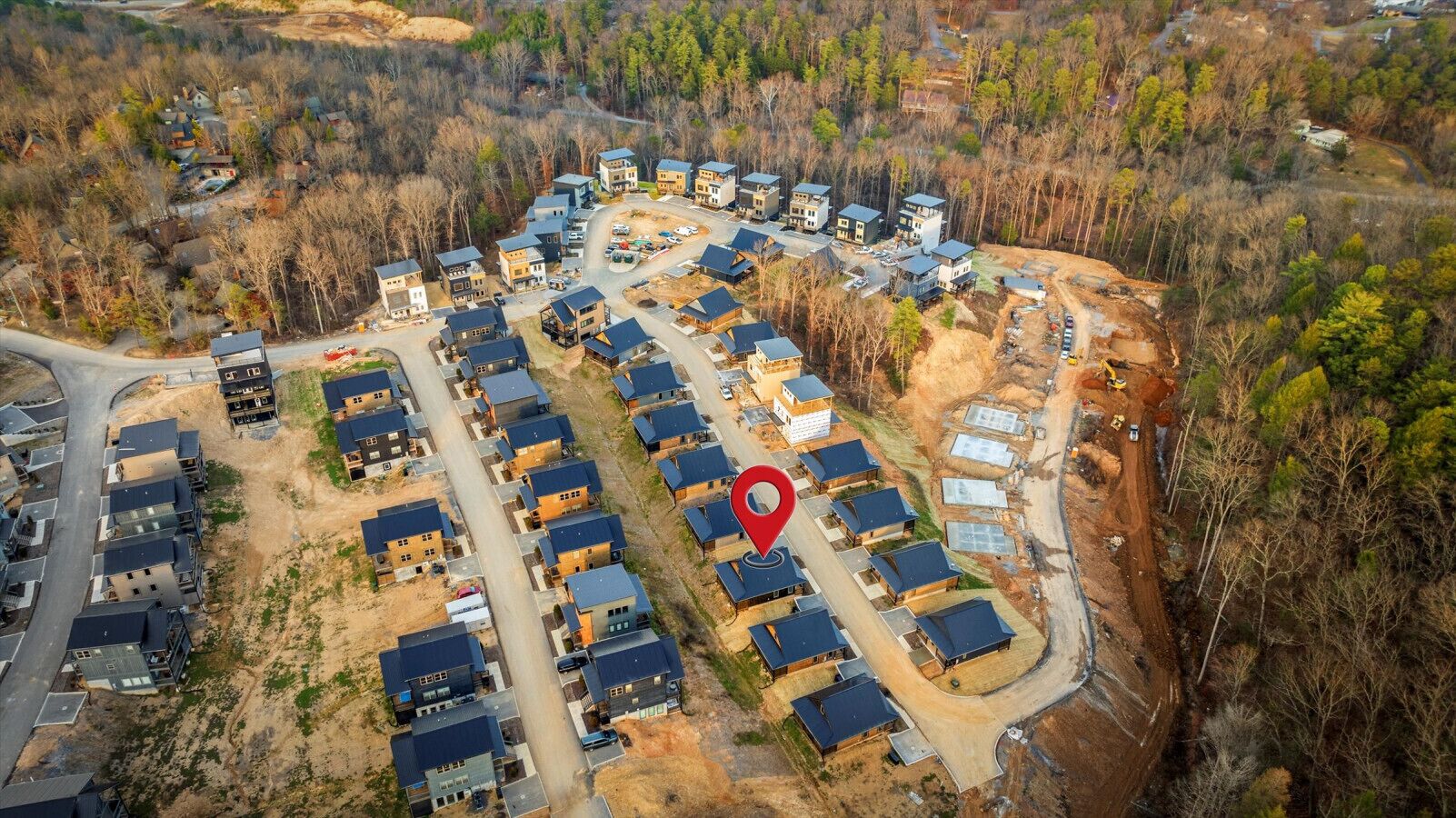 Vista aerea di una zona residenziale con diverse case, strade e un punto di riferimento indicato.