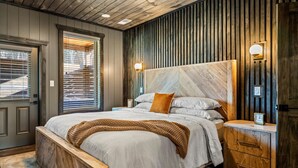 Un dormitorio con una cama grande, cabecera de madera, mesitas de noche y un velador.