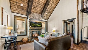 Un salón acogedor con chimenea, pared de piedra y techo de madera.