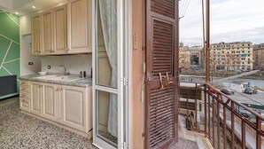 Eine Küche mit großem Fenster, ein Balkon mit Stadtblick und ein Spülbecken.