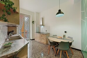 A kitchen with granite countertops, a wooden dining table with chairs, a hanging light fixture, and a view of the outdoors. - Apartment 'Janua Jungle House' with Balcony, Wi-Fi and Air Conditioning (Genova)