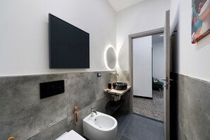 Un bagno moderno con uno specchio grande, un bidet e un lavandino.