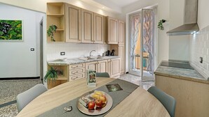 Eine moderne Küche mit Holzschränken, einer Arbeitsplatte aus Granit und einem Essbereich mit Tisch für zwei Personen.