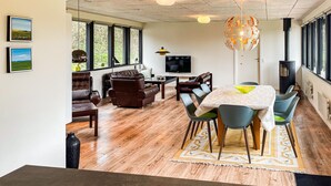 Een moderne woonkamer met een televisie, leren banken, een eettafel met stoelen en een open haard.