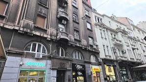A multi-story building with various storefronts, including a pharmacy and a DHL service center. - Elegant Apartment in Belgrade City Center – Stari Grad (Beograd)