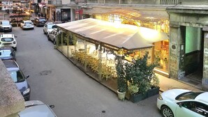 A street view with a covered outdoor seating area, parked cars, and buildings with balconies. - Elegant Apartment in Belgrade City Center – Stari Grad (Beograd)