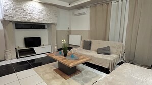 Un salon moderne avec un canapé, une table basse, un téléviseur et une cheminée.