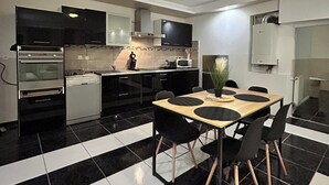 Une cuisine moderne avec un carrelage noir et blanc à motifs géométriques, une table à manger avec des chaises et des appareils électroménagers intégrés.