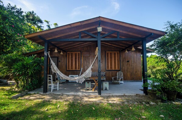 A wooden cabin with a covered porch, a hammock, and a small table.