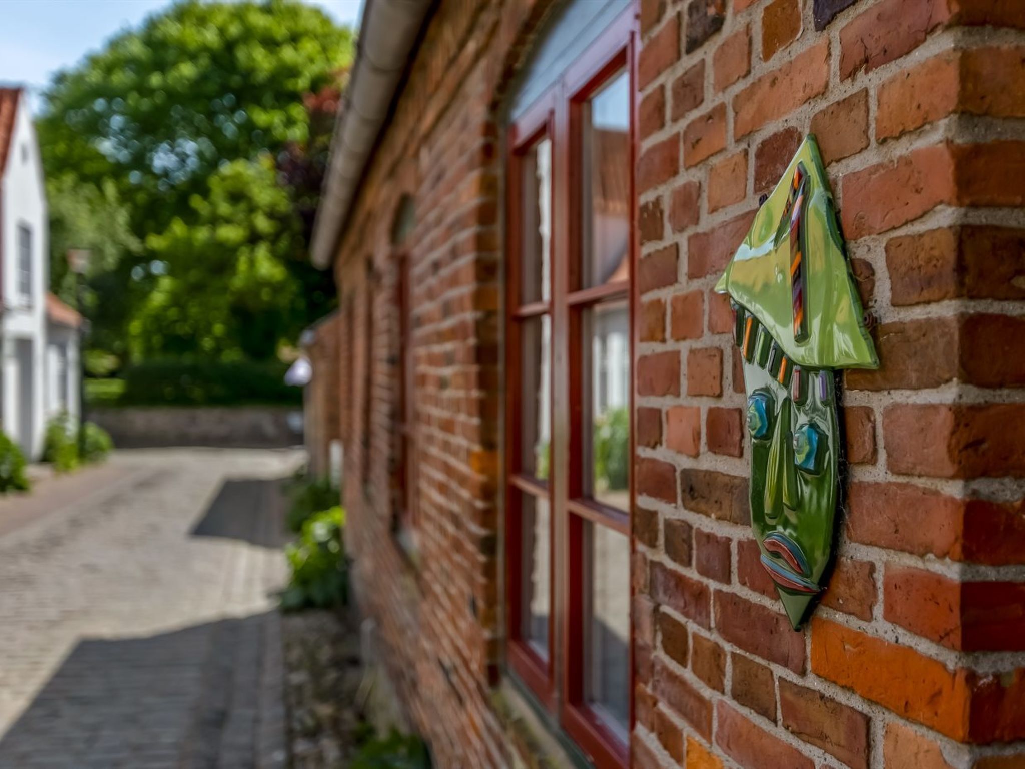Un edificio de ladrillo con una ventana y un adorno verde en la pared.