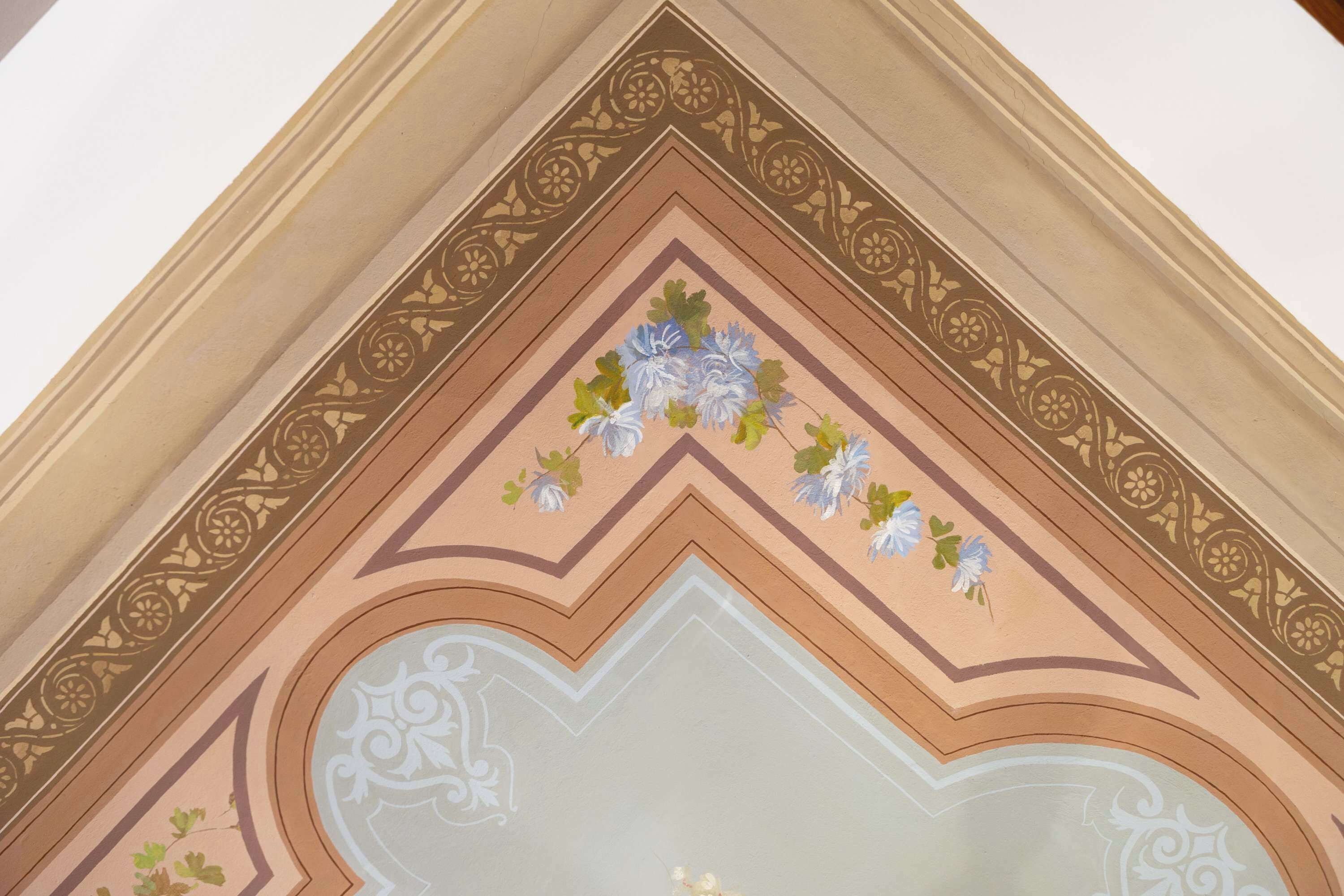 A ceiling with a decorative floral pattern and a geometric design.
