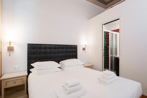 Una camera d'albergo con un letto grande, due comodini, un armadio e un angolo doccia.