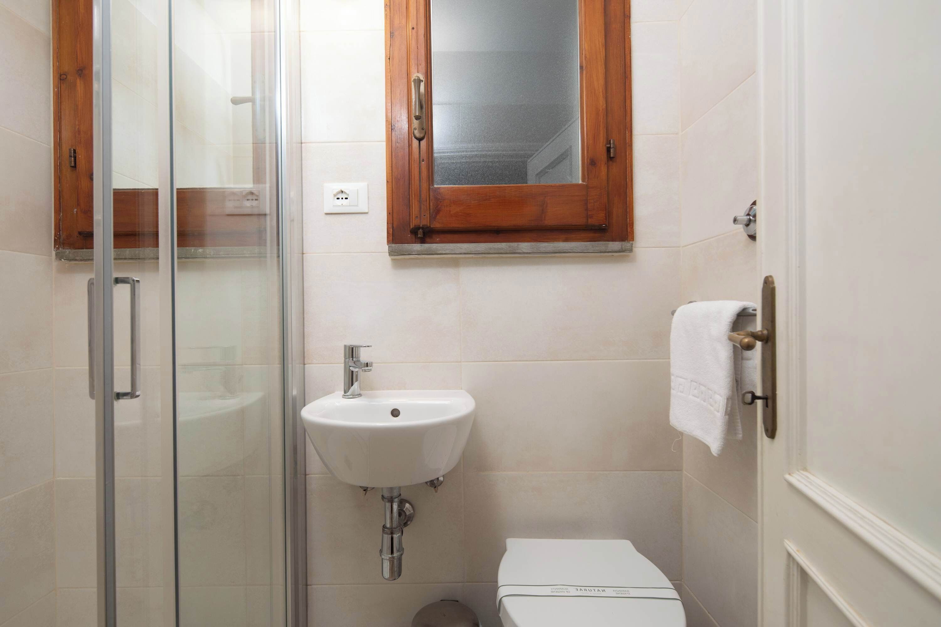 A bathroom with a glass shower enclosure, a white sink, and a toilet.
