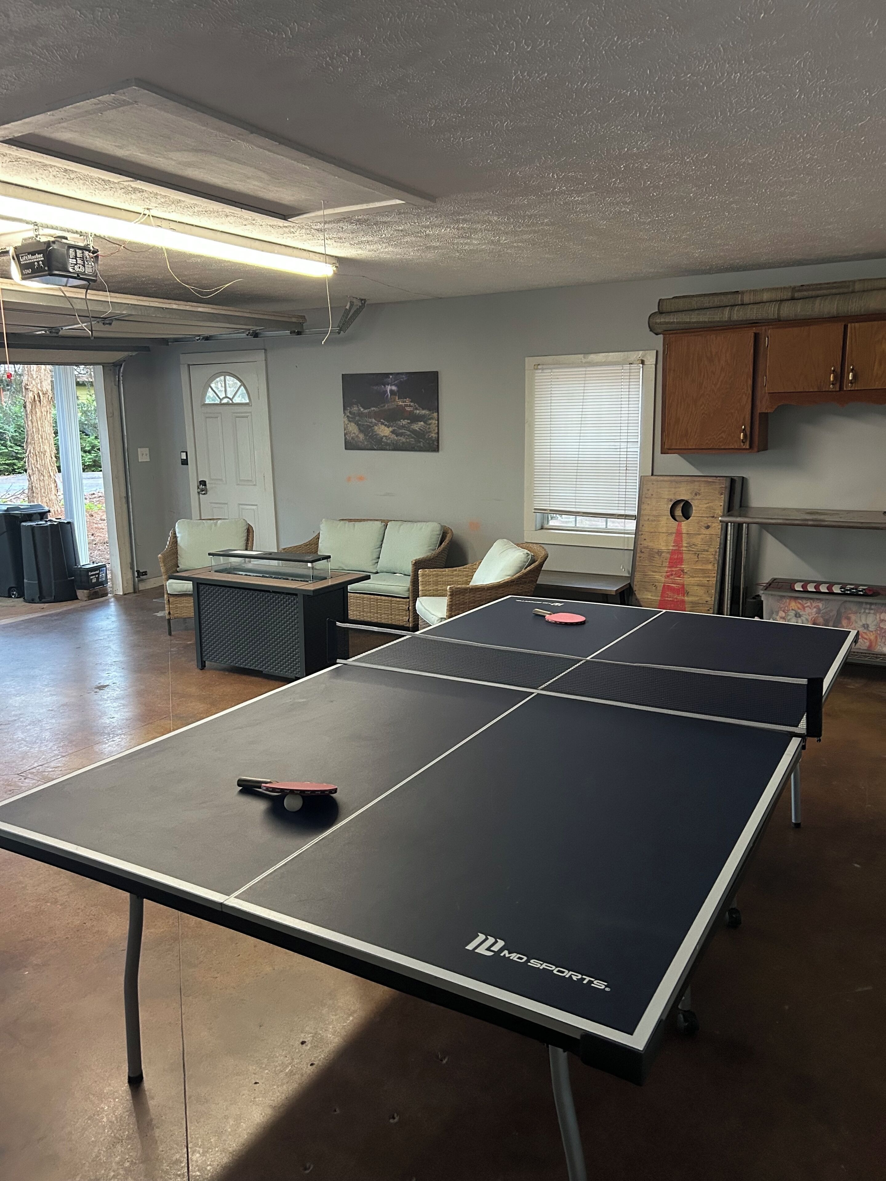 Una mesa de ping pong, un sofá, una ventana y una puerta en una habitación.