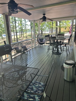 A covered outdoor patio with a grill, seating area, and ceiling fans.