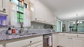 A kitchen with white cabinets, granite countertops, stainless steel appliances, and a window with curtains. - Cozy Pickwick Lake house overlooking Safe Harbor Aqua Yacht Marina Sleeps 10+ (Iuka)