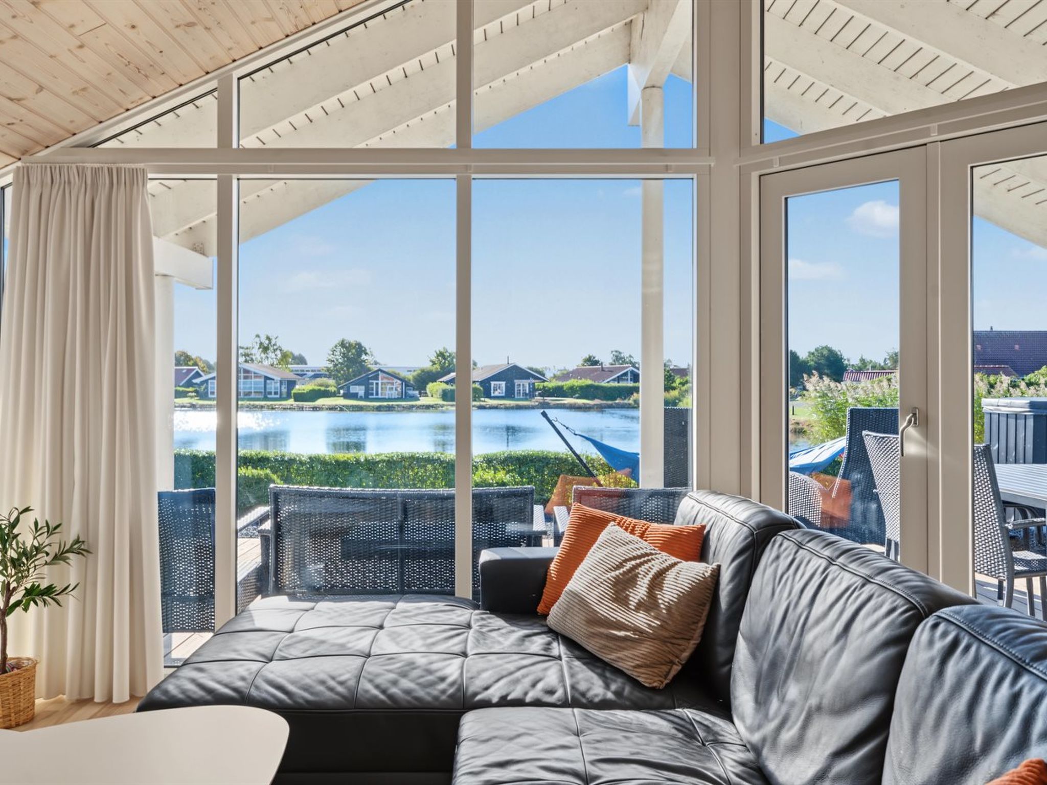 A sunlit room with a large window overlooking a body of water and houses.