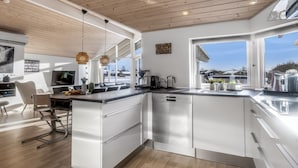 Een moderne keuken met een groot eiland, roestvrijstalen apparatuur en uitzicht op het buitenleven.