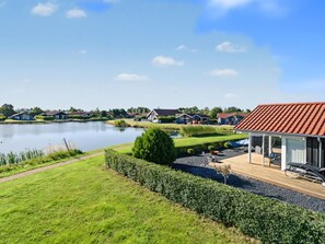 A lakeside property with a well-maintained lawn, a small pond, and a house with a red-tiled roof.