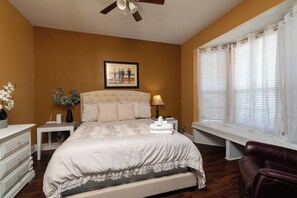 Cozy bedroom with a tufted headboard and charming window seat.
 - Fire Pit, Kids Toys + Fenced Yard - Family Getaway (Grand Prairie)