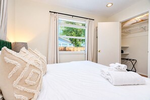 Une chambre d’hôtel avec un lit, une fenêtre avec des rideaux, une armoire et une vue sur la verdure.