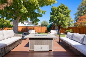 Eine Terrassenausstattung mit einem rechteckigen Feuerkorb-Tisch, zwei Korbsitzen und einer grünen Rutsche.