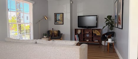 Una sala moderna con un sofá, televisión y estantería.