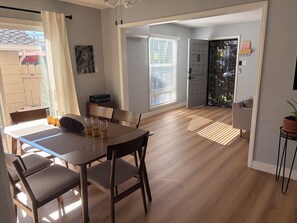 Un comedor con mesa y sillas de madera, un cuadro en la pared y vistas al exterior.