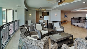 A spacious lounge area with wicker furniture, a ceiling fan, and a view of the outside. - Palisades Palms Tw1012 - Sea Escape (Galveston)