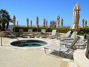 A pool area with lounge chairs, umbrellas, and a sign indicating a spa. - Palisades Palms Tw1012 - Sea Escape (Galveston)