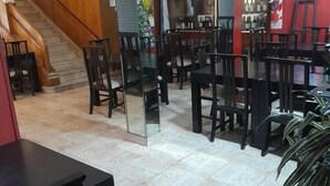 A restaurant with a staircase, multiple tables and chairs, and a tiled floor. - Gran Hotel Turismo (Mendoza)
