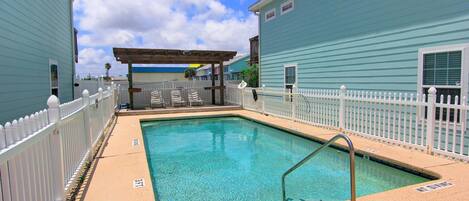 A pool area with a 'NO DIVING' sign, surrounded by a white fence, and adjacent to a building with a blue exterior.