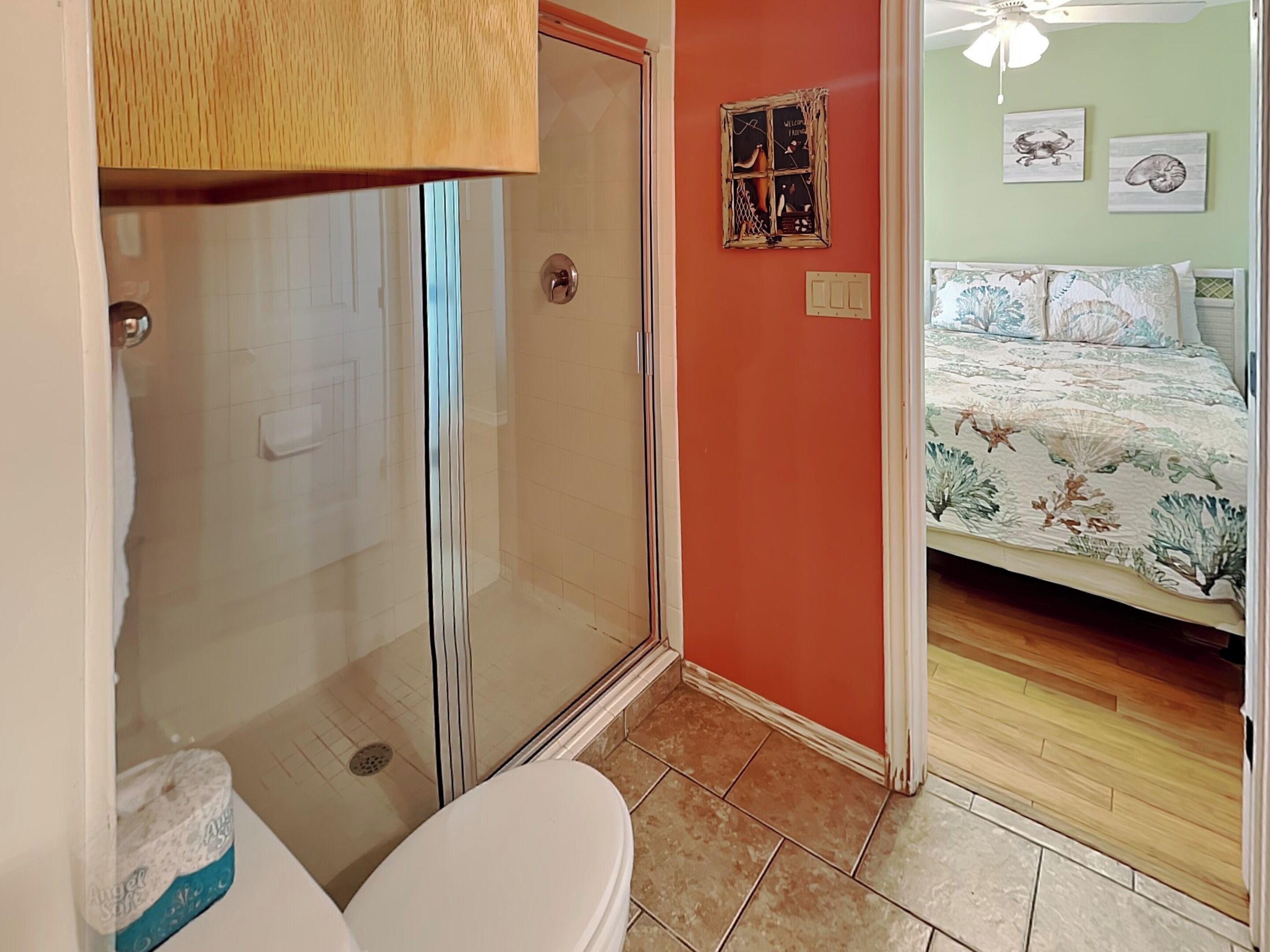A bathroom with a glass shower enclosure, a toilet, and a sink.