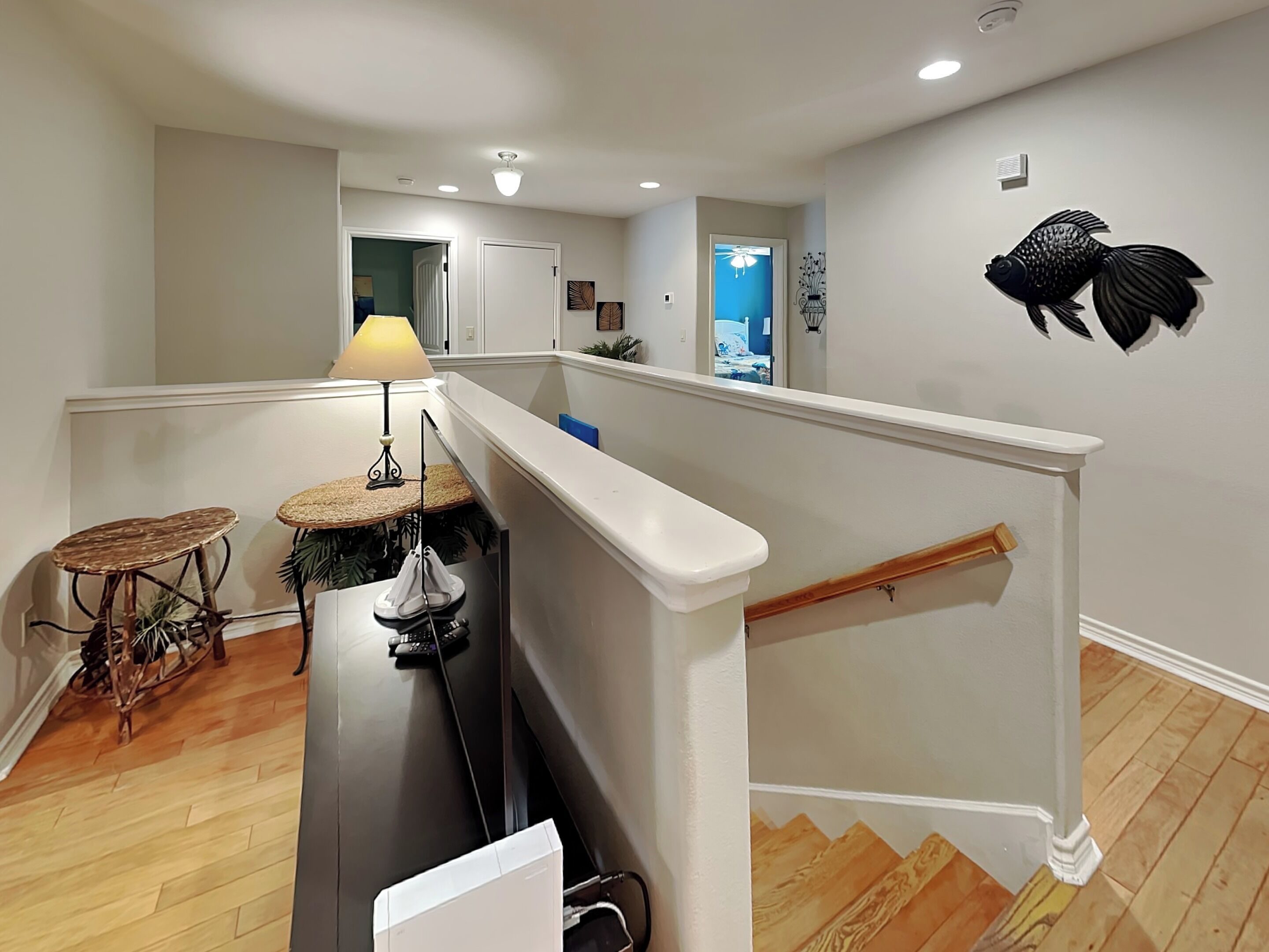 Una cocina moderna con una isla central, un comedor con una mesa pequeña y sillas, y una escalera con barandilla.