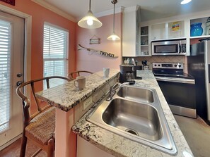 A kitchen with a sink, stove, microwave, and a coffee maker. - Sandy Seashell (Port Aransas)