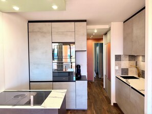 A modern kitchen with a built-in oven, a glass backsplash, and a wooden floor. - Le Panoramique Cap Esterel sea view (Saint-Raphaël)