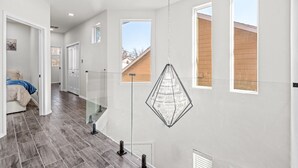 A modern interior with a staircase, a hanging chandelier, and large windows. - Downtown Houston escape with en-suites (Houston)