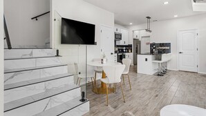 A modern kitchen with white cabinetry, a built-in oven, and a large island with bar stools. - Downtown Houston escape with en-suites (Houston)