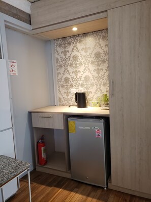 A compact kitchen with a refrigerator, a coffee maker, and a fire extinguisher. - SUIT WITH THE BEST VIEW OF THE HISTORIC CENTER OVERLOOKING THE PANECILLO (Quito)