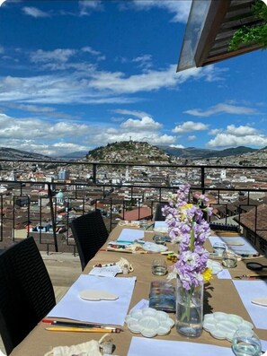 A dining table set outdoors with a cityscape view, including a hill with a statue. - SUIT WITH THE BEST VIEW OF THE HISTORIC CENTER OVERLOOKING THE PANECILLO (Quito)
