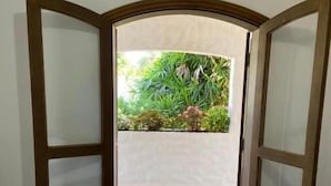 An open door leading to a balcony with a tiled floor and a view of greenery. - Pousada Villa Novo Tempo  (Guarujá)