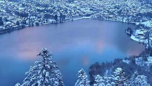 Ein Panoramablick auf eine verschneite Stadt mit einem See in der Mitte, umgeben von Bergen.
