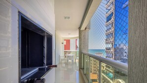 Een gang met een glazen balustrade, een raam met een zwarte lijst en uitzicht op een gebouw met een blauwe gevel.
