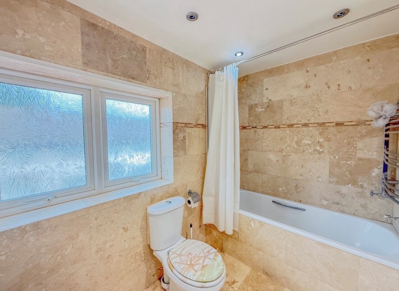 Ein Badezimmer mit Toilette, Badewanne und einem Fenster mit Milchglas.