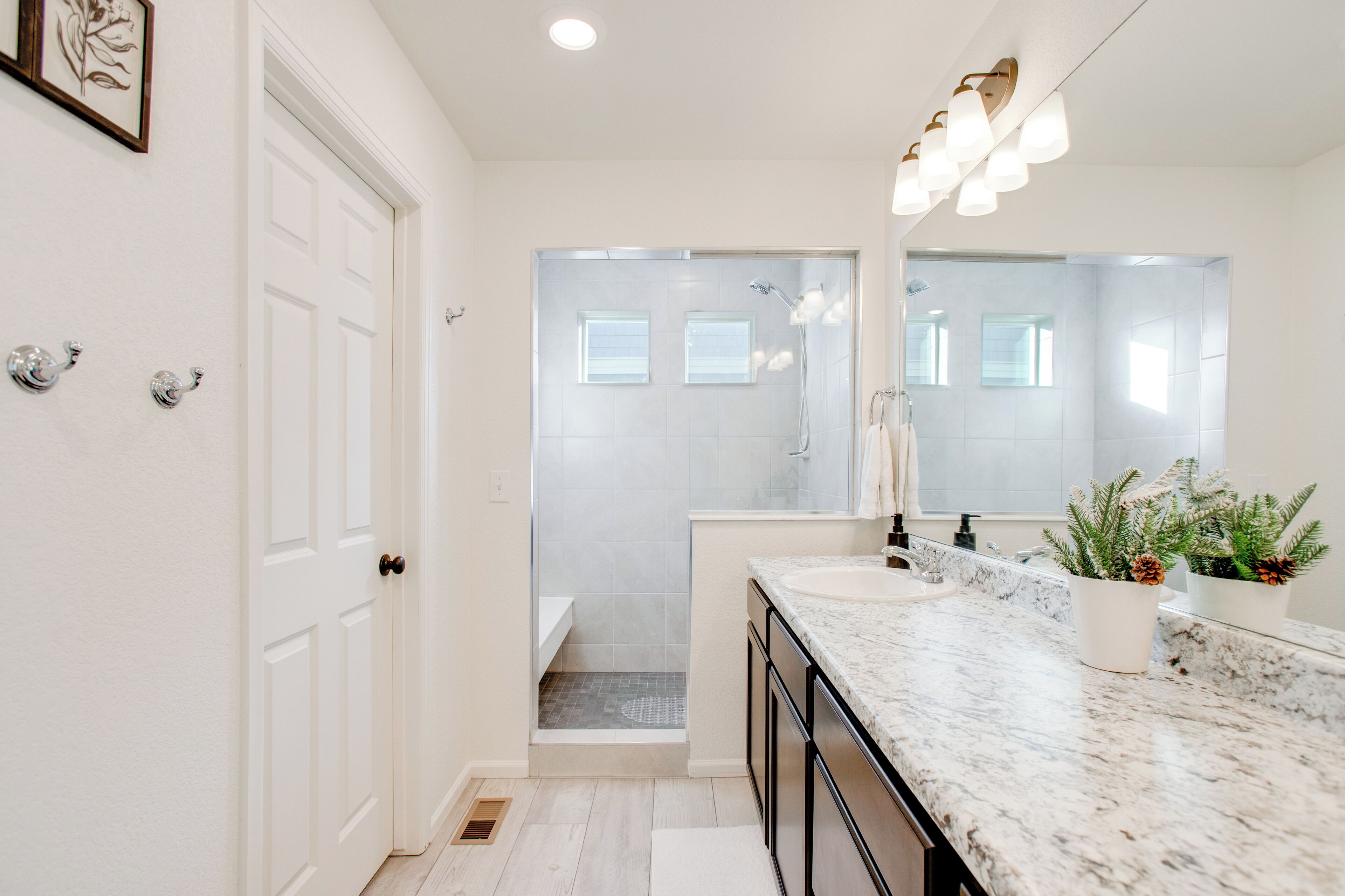 Une salle de bain moderne avec un grand miroir, deux lavabos et un espace douche.