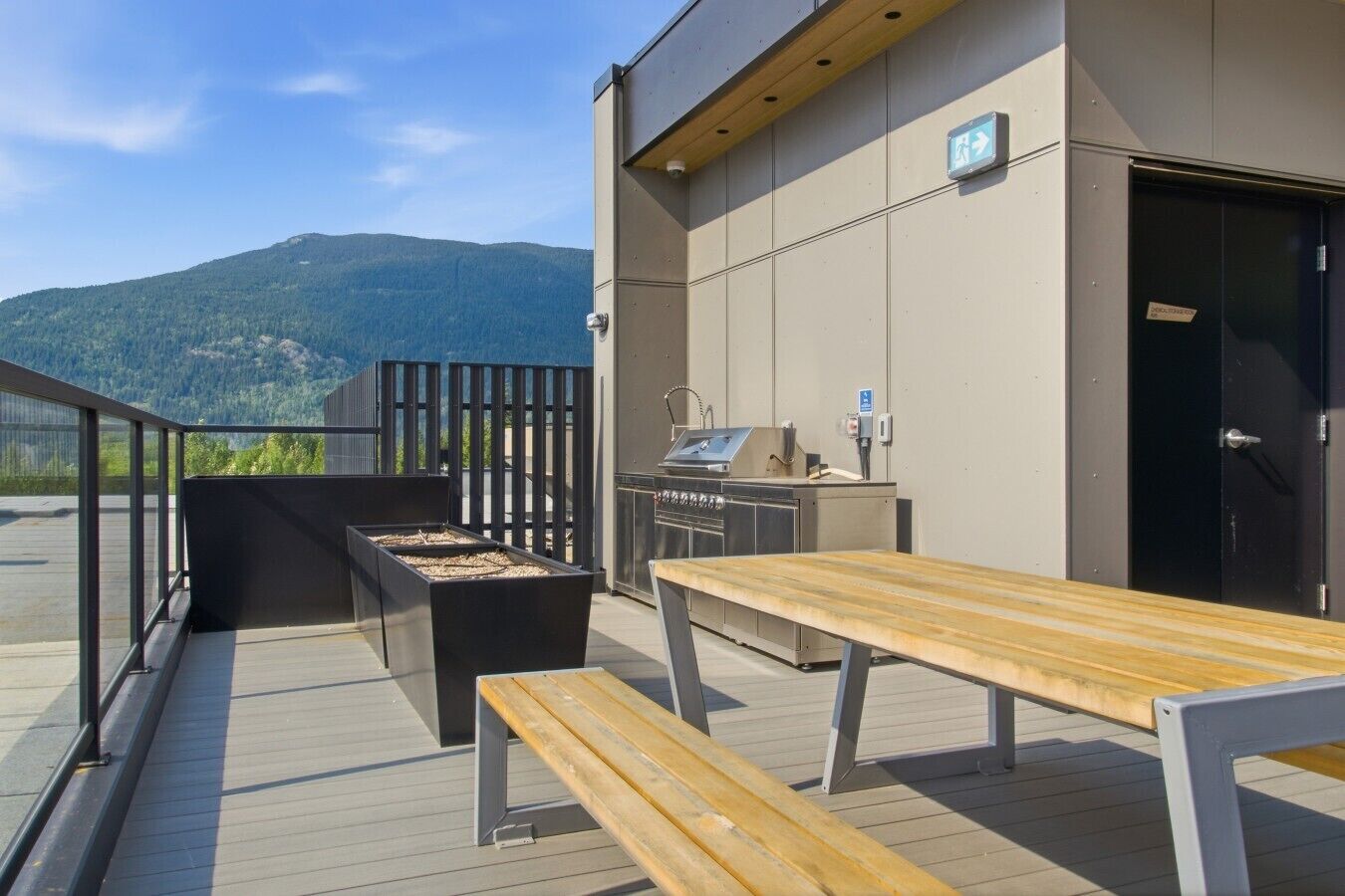 Une terrasse extérieure avec un barbecue, des sièges et une vue sur les montagnes.