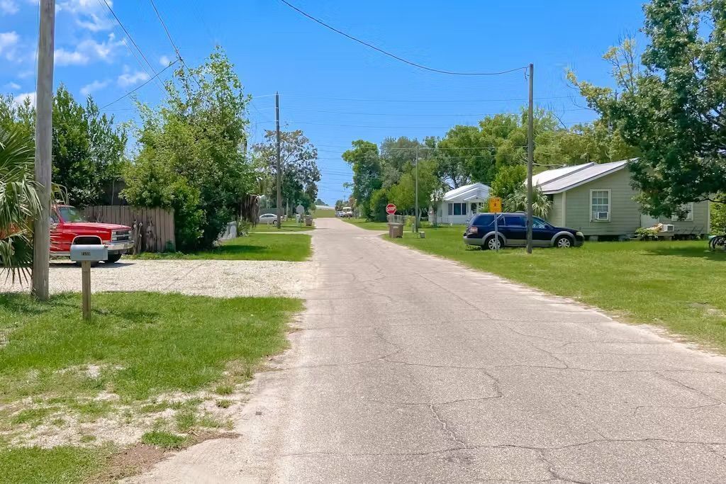 A quiet residential street with houses on both sides, a mailbox, and a stop sign.